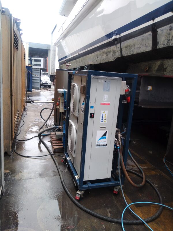 Temporary chiller unit connected to a yacht hull during dry dock marine HVAC hire project.